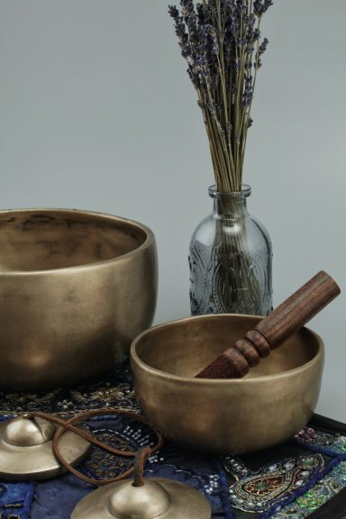 Zwei bronzene Schalen mit einem Holzstab, daneben eine Glasvase mit Lavendel.