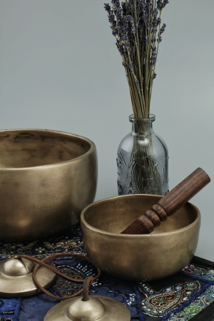 Zwei bronzene Schalen mit einem Holzstab, daneben eine Glasvase mit Lavendel.