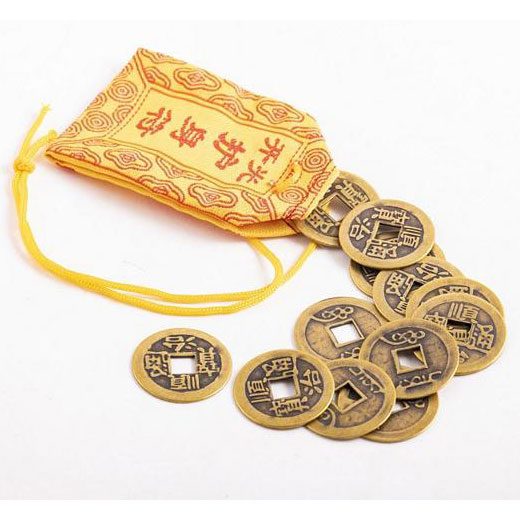 Glücksmünzen Goldene chinesische Münzen liegen neben einem roten Säckchen mit goldenen Zeichen.