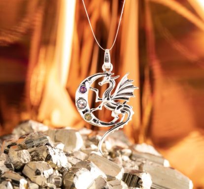 Silberner Drachenanhänger mit bunten Edelsteinen vor glitzerndem Hintergrund.