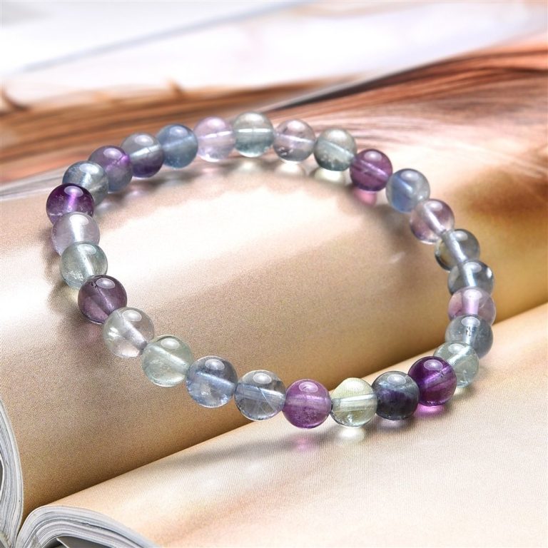 Bunte Armbänder aus verschiedenen farbigen Perlen auf einem offenen Buch.